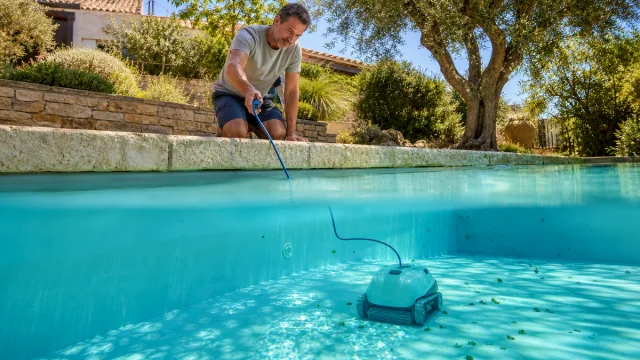 Propriétaire récupérant un robot nettoyeur dans une piscine résidentielle