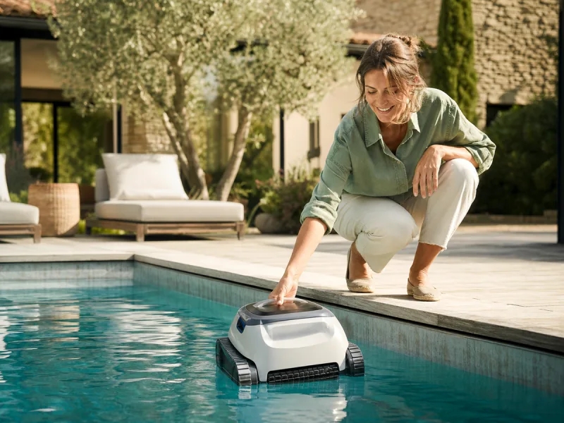 Habitante déposant facilement un robot de piscine générique sans câble dans le bassin